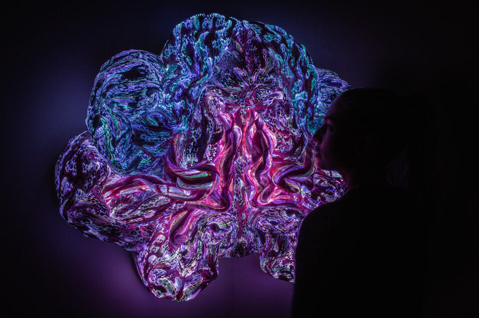 The artwork Andetag no. 13 with a person in the frame showing the textile sculpture's scale.