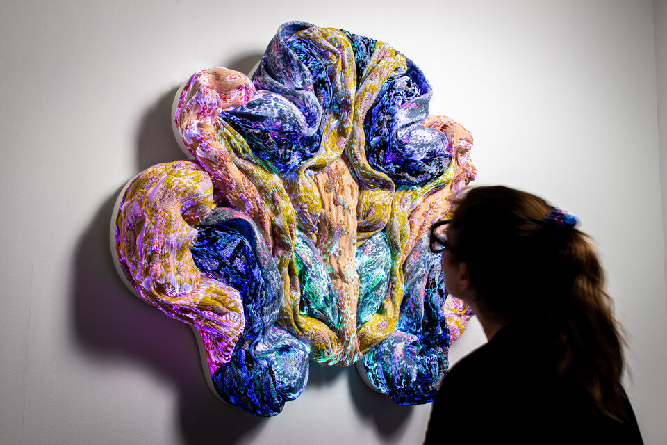 The artwork Andetag no. 20 with a person in the frame showing the textile sculpture's scale.