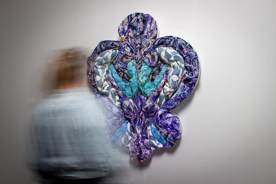 The artwork Andetag no. 22 with a person in the frame showing the textile sculpture's scale.