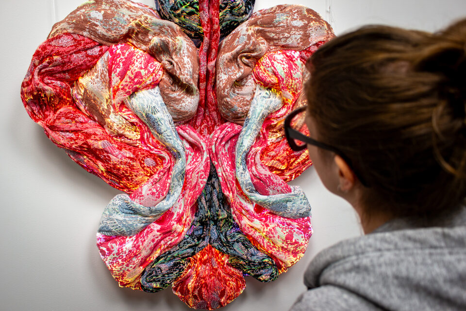 The artwork Andetag no. 24 with a person in the frame showing the textile sculpture's scale.