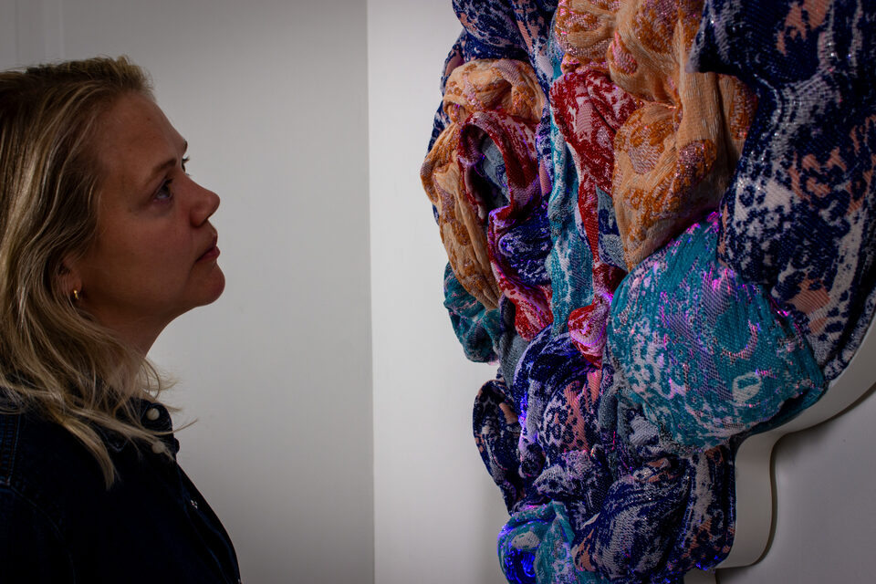 The artwork Andetag no. 33 with a person in the frame showing the textile sculpture's scale.