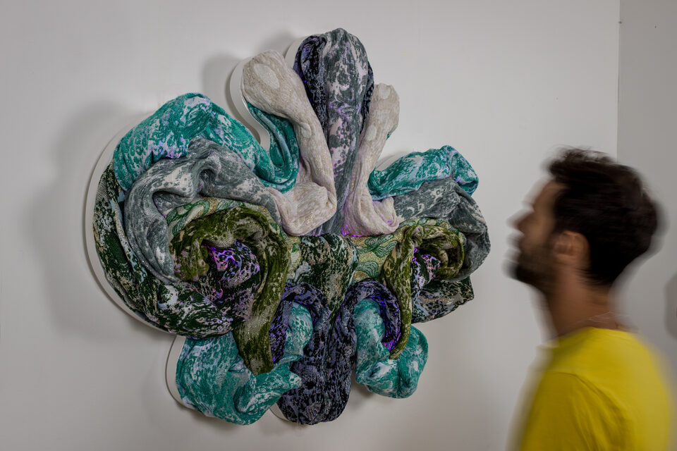 The artwork Andetag no. 38 with a person in the frame showing the textile sculpture's scale.