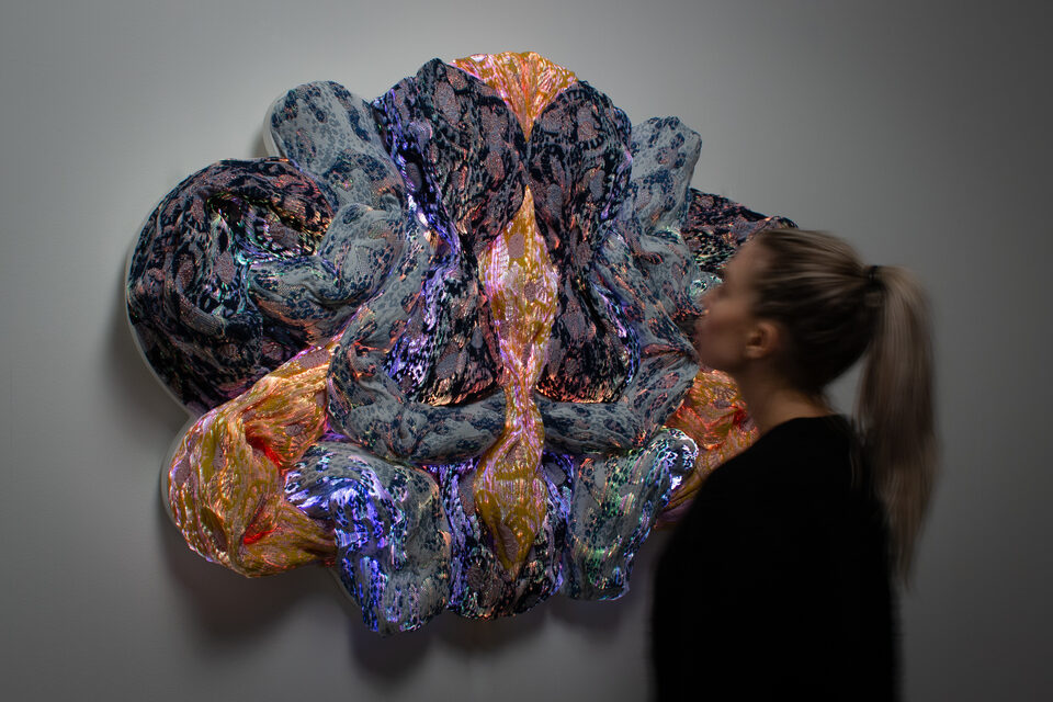 The artwork Andetag no. 5 with a person in the frame showing the textile sculpture's scale.