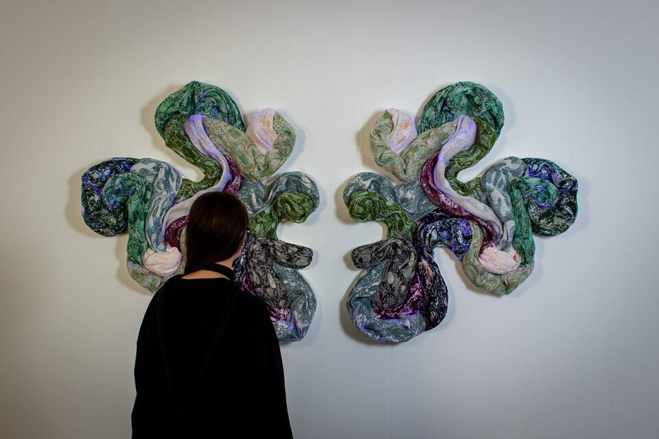 The artwork Andetag no. 50 with a person in the frame showing the textile sculpture's scale.