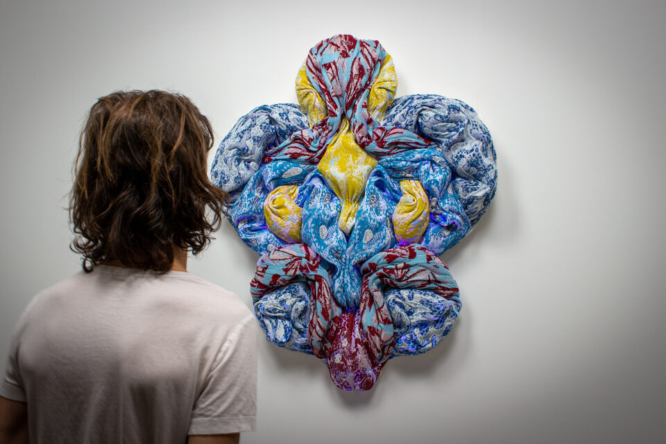 The artwork Andetag no. 7 with a person in the frame showing the textile sculpture's scale.