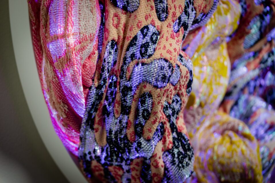 Close-up of peach-and-pink jacquard textile at ANDETAG Stockholm with dark leopard-like patterning