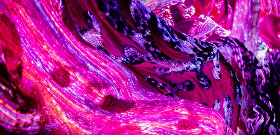 Close-up of Andetag no. 27, sweeping folds of optical fibre textile in magenta and deep purple glowing from within at ANDETAG museum