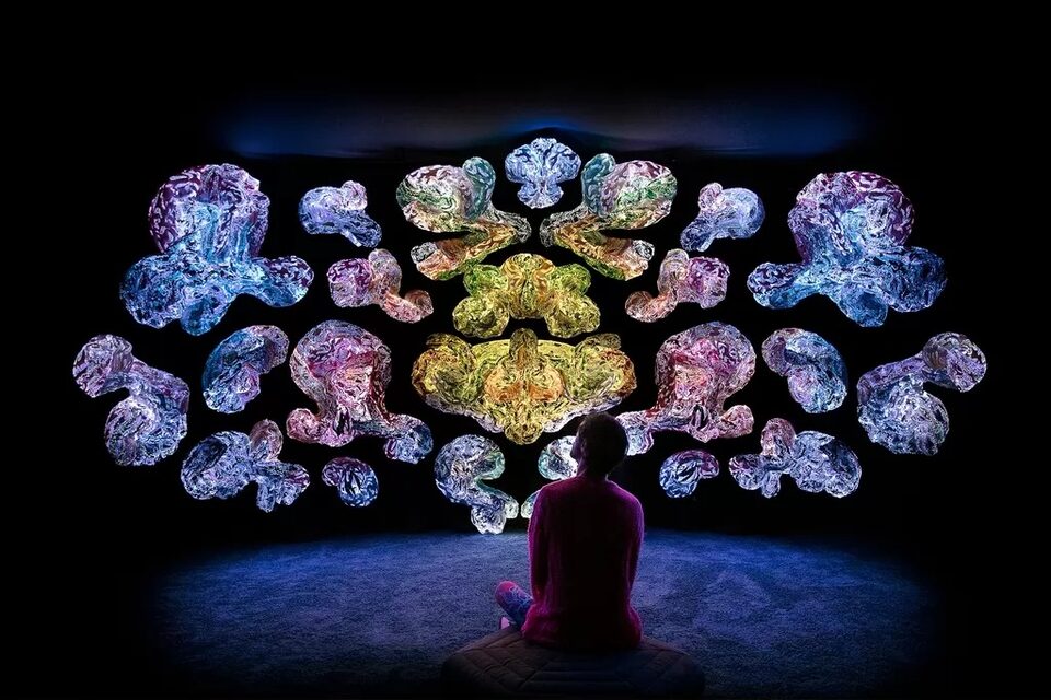 Visitors in low light among luminous textile art at ANDETAG
