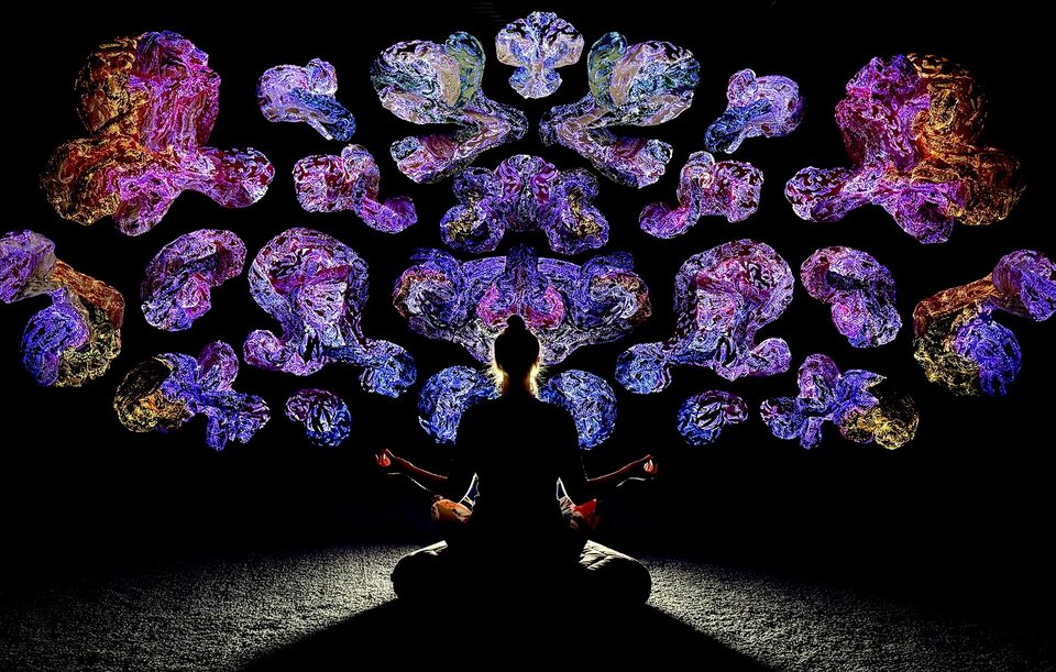 Person sitting still, surrounded by luminous textile art at ANDETAG